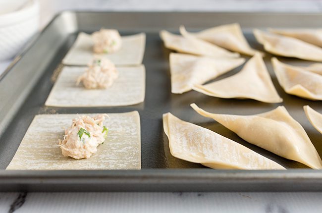 wonton wrappers with filling on a cookie sheet
