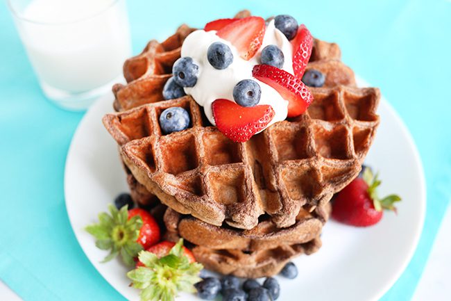Large white plate of protein powder waffles with glass of milk in background