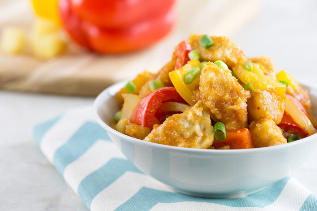 baked sweet and sour chicken served in a white bowl garnished with green onions