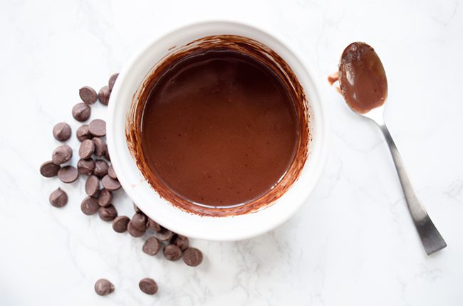 A white mug of chocolate melted to top cosmic brownies