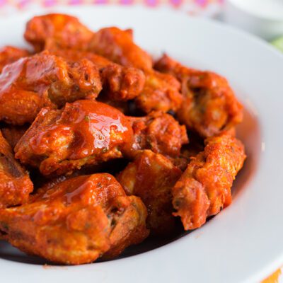 A close up picture of a large white bowl filled with chicken wings