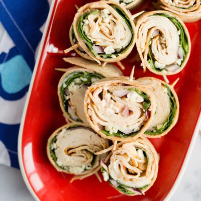 Up close picture of a red platter filled with buffalo chicken pinwheels appetizer