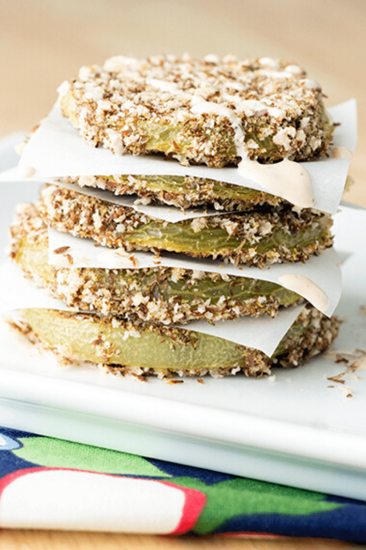 A stack of fried green tomatoes on a white platter sitting on a colorful napkin