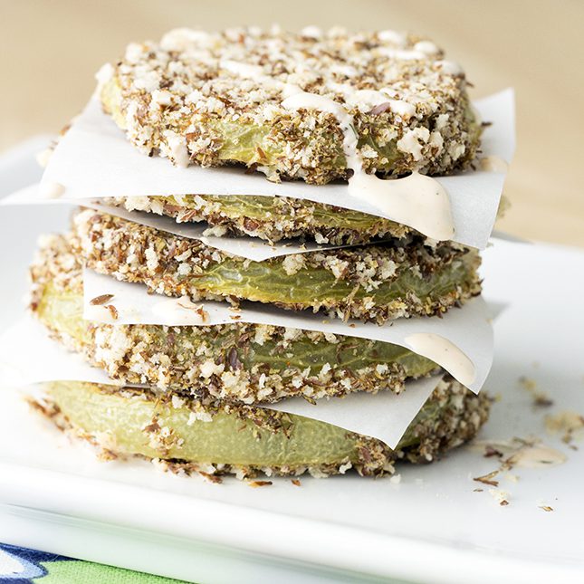 A small stack of baked green tomatoes separated by parchment paper pieces
