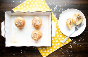 Overhead picture of baked apples in white baking dish sitting on yellow cloth