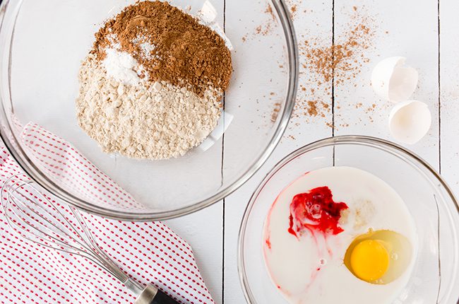 Ingredients for red velvet donuts in bowls laying on white counter
