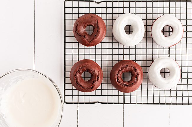 Red Velvet Donuts being dipped into glaze