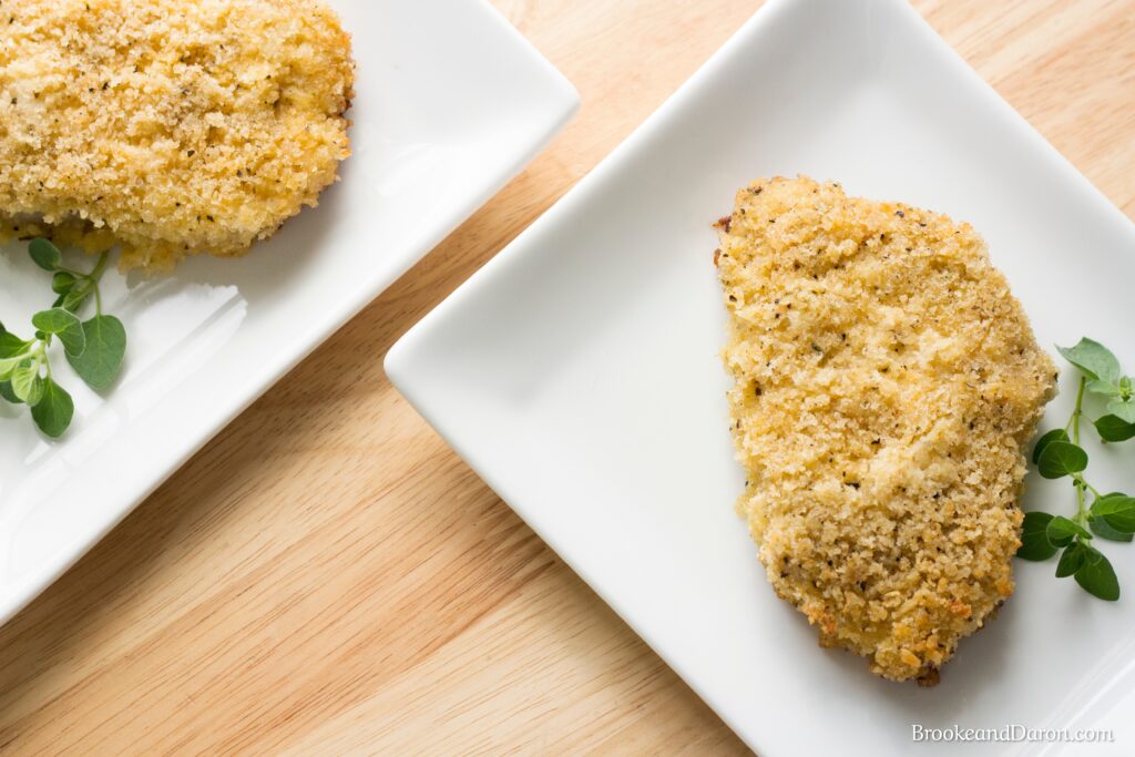 Parmesan pork chop on white plate with parsley