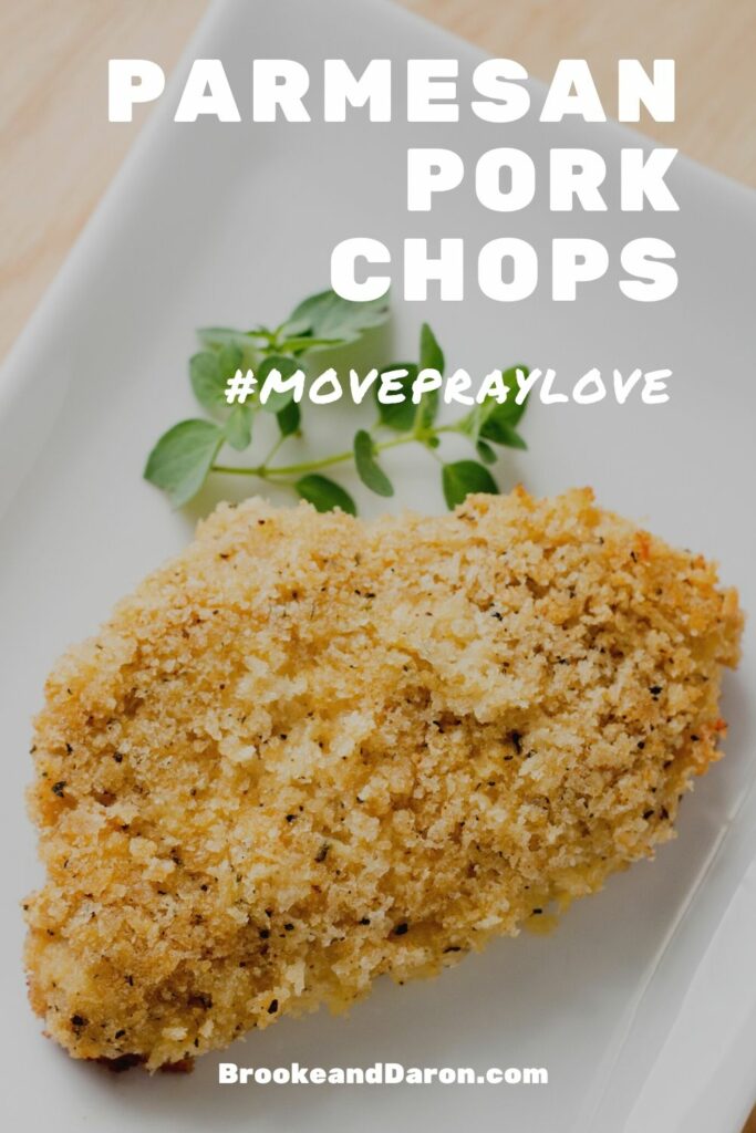 Parmesan pork chop on white plate with parsley