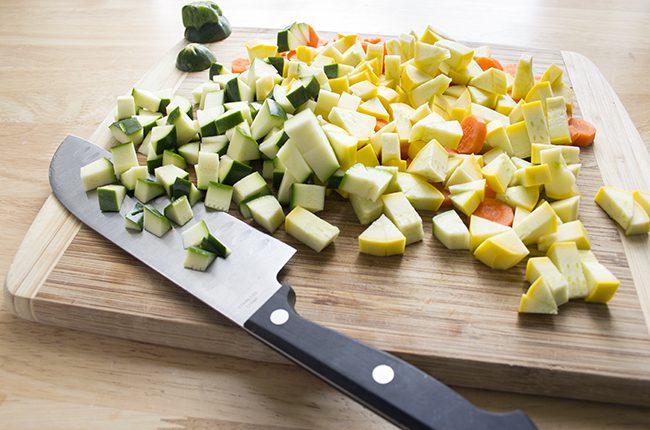 Squash and carrots on a cutting board being cut