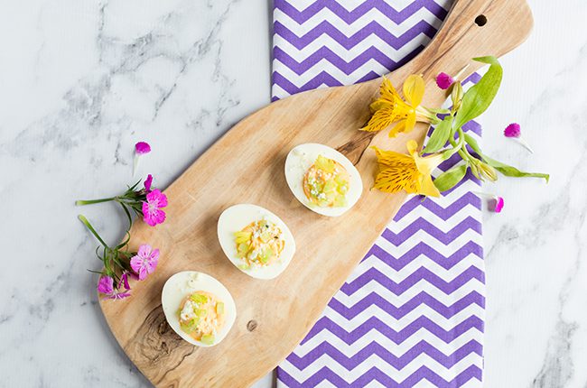 buffalo deviled eggs on a cutting board with a purple and white towel