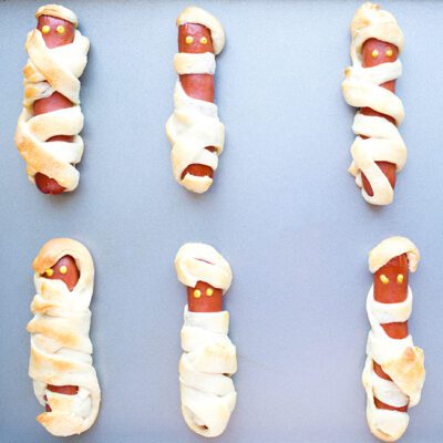 square picture of mummy hot dogs on baking sheet