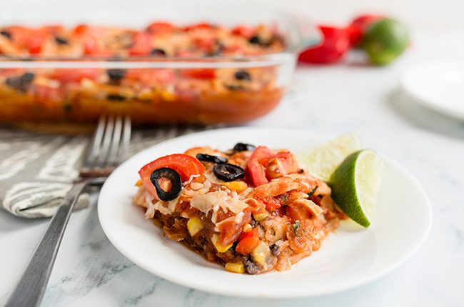 A single serving of mexican lasagna in front of the full casserole