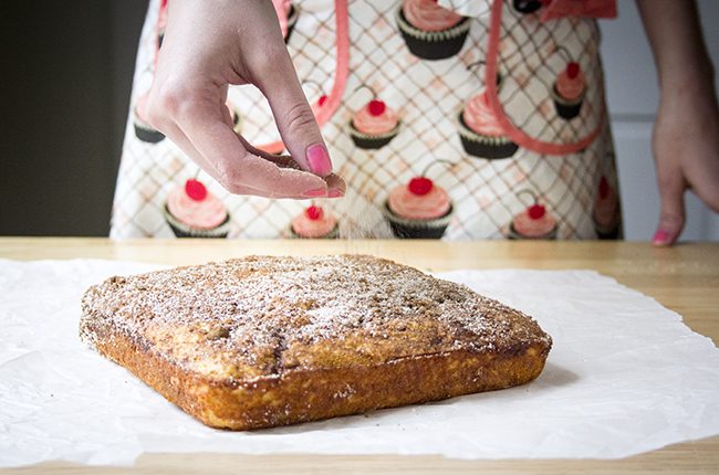 Cinnamon sugar being sprinkled over the top of coffee cake