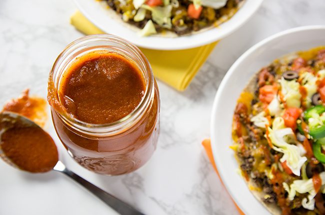 Overhead picture of a jar of enchilada sauce in a jar next to mexican dish