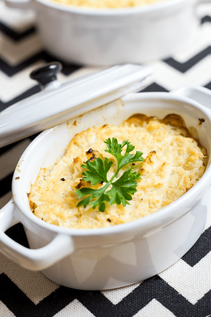Overhead picture of a white crock of mashed cauliflower on a black chevron print cloth