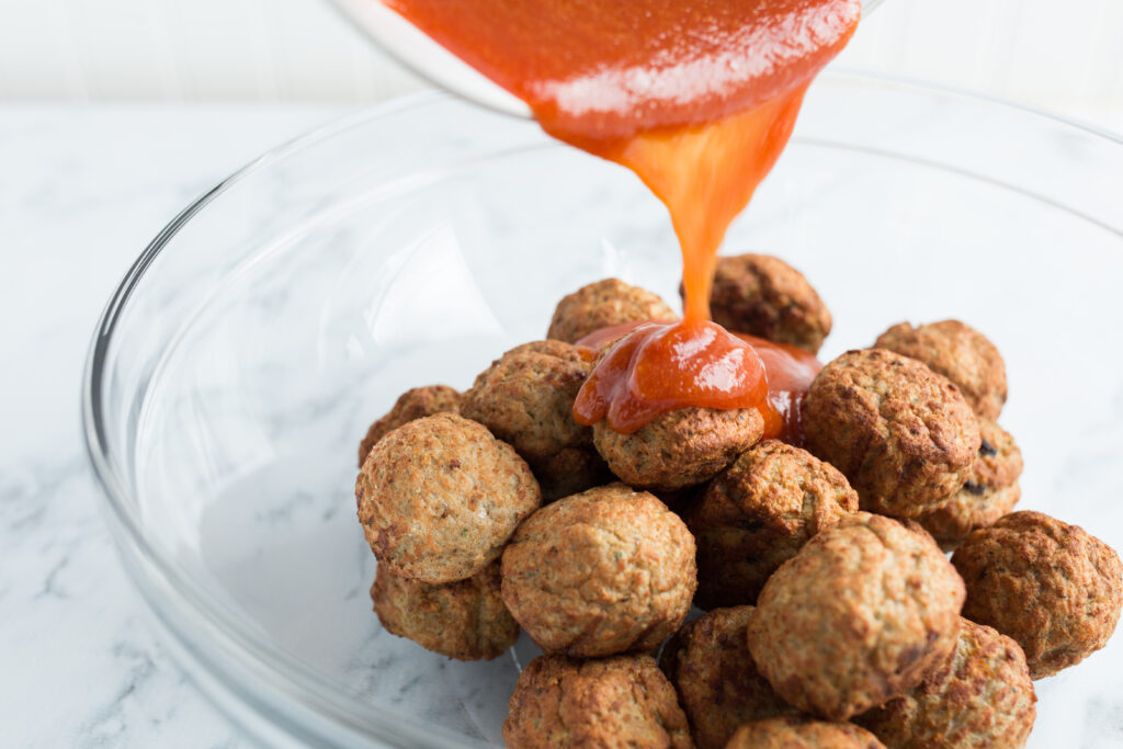 Pouring sauce over meatballs for bourbon bbq