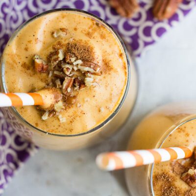 Overhead close up picture of pumpkin smoothie in glasses sitting on a purple cloth
