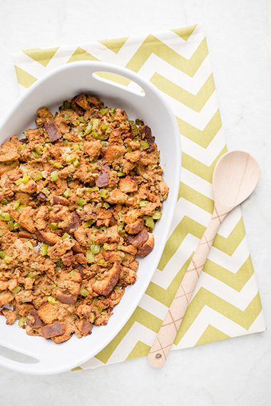 Overhead picture of white casserole dish on green and white cloth filled with sage and onion stuffing
