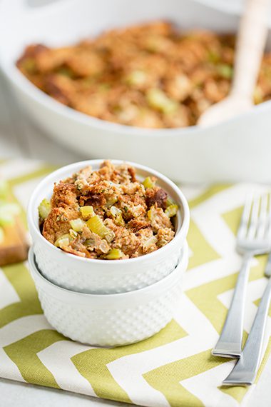 Up close picture of stuffing in white bowl sitting on green and white napkin
