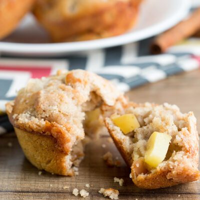Square up close picture of apple cinnamon muffin torn in half to show inside apple pieces