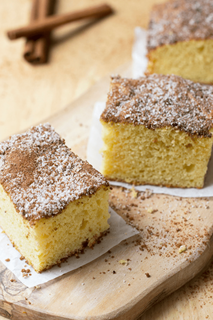 Three slices of cinnamon coffee cake on cutting board with cinnamon sticks in background