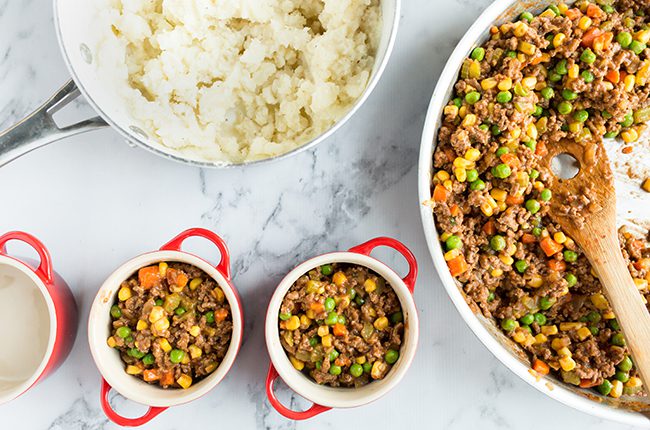 Filling mini crocks with ingredients for shepherds pie recipe