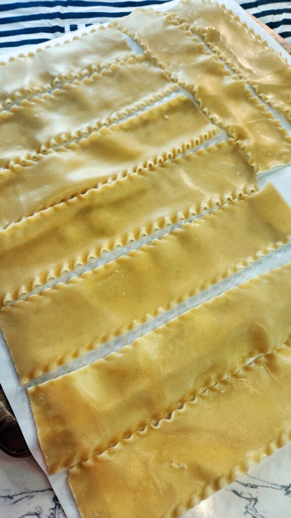 Cooked lasagna noodles lying flat on parchment paper